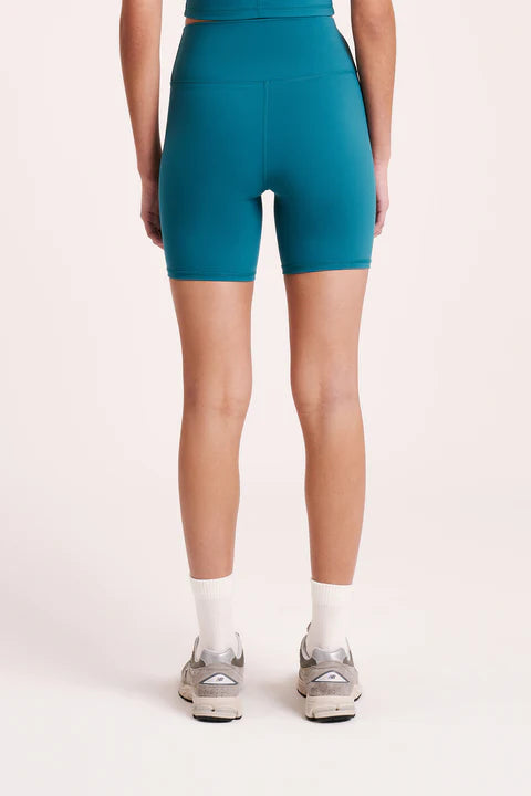 The Nude Active Bike short is made from a recycled performance fabrication with a matte, velvety finish. This fabric has 4-way stretch and has been designed to sculpt and smooth whilst providing full coverage and support for low-impact activities. Silhouette is form-fitting and high waisted with length finishing mid-thigh. Features include a double layer high rise waist, our signature nl. branded logo and a hidden waistband pocket at the centre back.