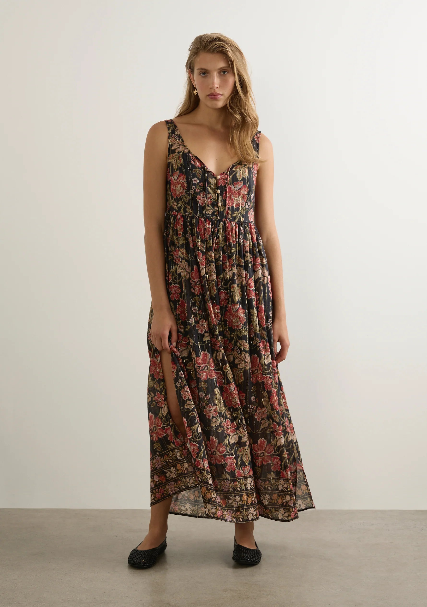 The Beachside Maxi Dress, an all-time Auguste best-seller for a reason, returns in the black-based Vesper Floral with striking border print detail. Designed with a round neckline, specialty gold button-front closure, and a neck tie finished with bead ends for a delicate touch. With a relaxed fit that falls to a floaty hem and side splits for added movement, this shimmering maxi is crafted from our trademark cotton with gold lurex thread woven throughout. A timeless silhouette reimagined, it’s the summer sta