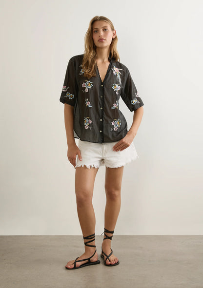 The Viola Blouse in black is another work of art from the talented Balinese artisans that Auguste’s founder, Ebony, has collaborated with for nearly 20 years. A testament to timeless craftsmanship, this blouse features a collar stand with a V-neckline, a center front button closure, and delicate scallop embroidery along the neckline and opening. Intricate embroidered detailing adds to its refined elegance, while the 100% cotton, semi-sheer, non-stretch fabric offers a soft drape and luxurious hand feel. Des