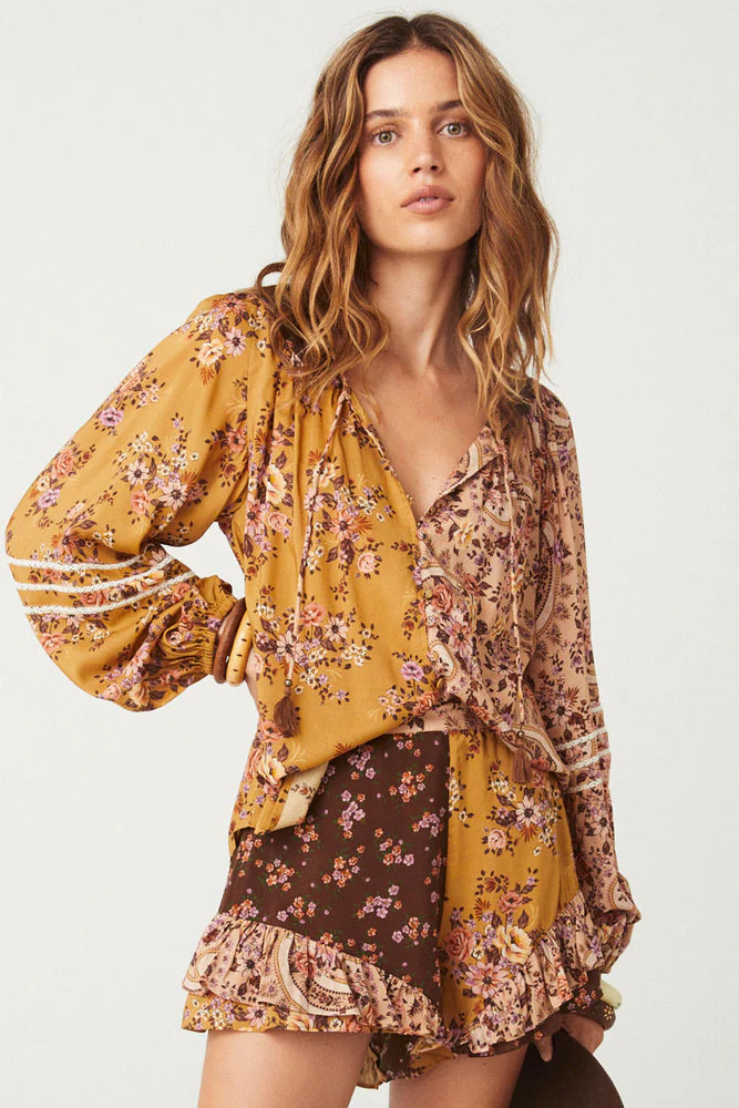 The Melody Blouse in Woodstock is crafted for the rebel hearts. Our newest blouse features a unique patchwork print placement from the design team ~ our honeyed amber print to one side, our rambling florals in pink and cream to the other with our retro brown and ditsy floral print across the back yoke complete this statement style and echo the free spirit of our rebel muse. Inserted ladder lace frames the billowing sleeves, a button down front offers styling versatility while the neck line includes ties wit