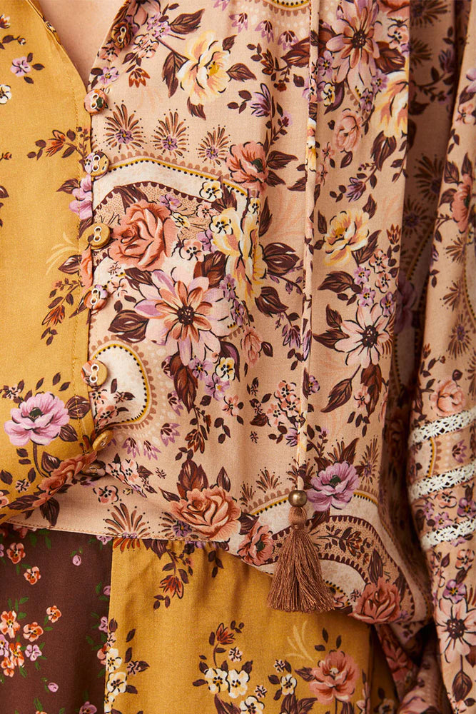 The Melody Blouse in Woodstock is crafted for the rebel hearts. Our newest blouse features a unique patchwork print placement from the design team ~ our honeyed amber print to one side, our rambling florals in pink and cream to the other with our retro brown and ditsy floral print across the back yoke complete this statement style and echo the free spirit of our rebel muse. Inserted ladder lace frames the billowing sleeves, a button down front offers styling versatility while the neck line includes ties wit