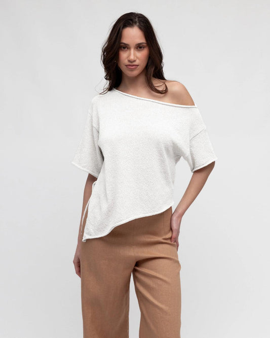 Effortless style meets everyday comfort. The Asy Bounce Knit Top is designed with a relaxed drape and an asymmetrical hemline, giving it a modern edge. Crafted from a soft textured knit, it features a wide neckline that can be styled off-the-shoulder for an easy, laid-back vibe. Perfect for pairing with tailored pants, denim, or skirts, this versatile piece moves seamlessly from casual days to elevated evenings.