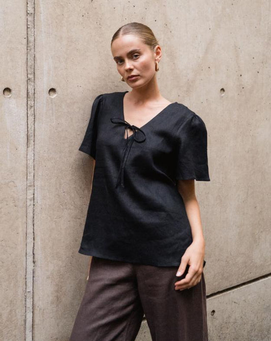 The Delight Top - &nbsp;Black

The White Closet Black Linen Top combines comfort and chic with its breathable linen fabric and floaty sleeves. Its loose fit allows for a relaxed style, while the elegant front tie-up across the bust adds a feminine touch. Wear it loose for effortless ease or tuck it in to highlight your silhouette. This versatile top is perfect for elevating your everyday look with understated sophistication.