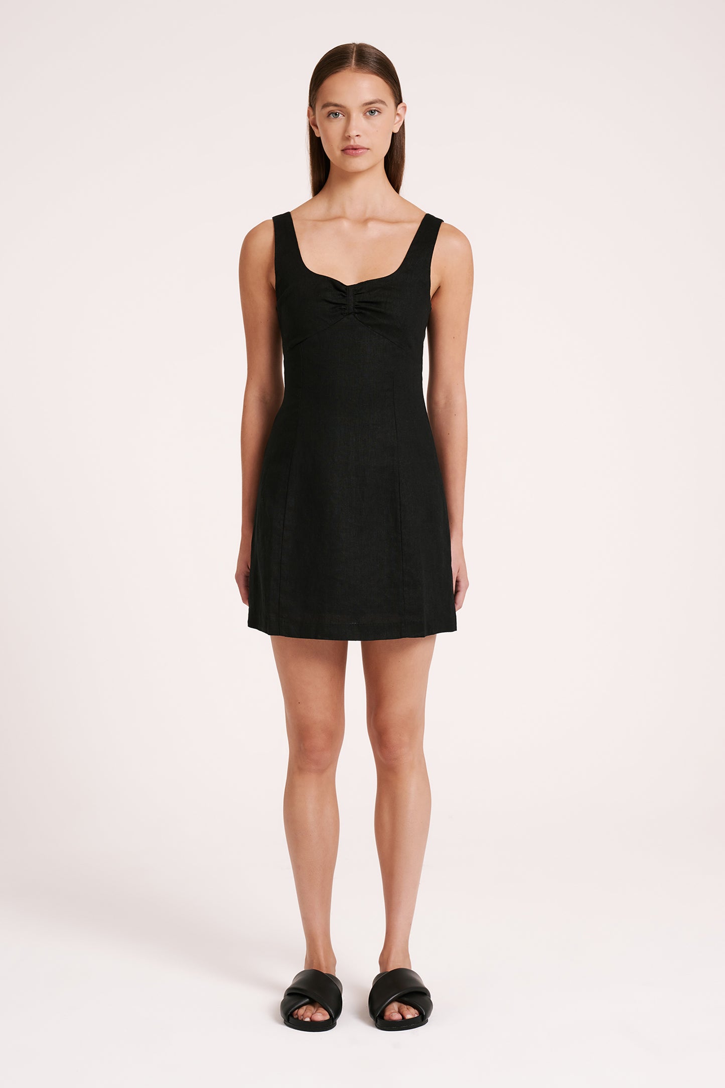 The Sibyl Linen Dress in black is made from 100% linen which has been washed for a soft, breathable hand feel. The silhouette fits close to the body with an A-line mini skirt. Features include a soft square neckline, panelled under bust seam with ruching and thick straps with adjusters. Dress is fully lined with a centre back zipper.