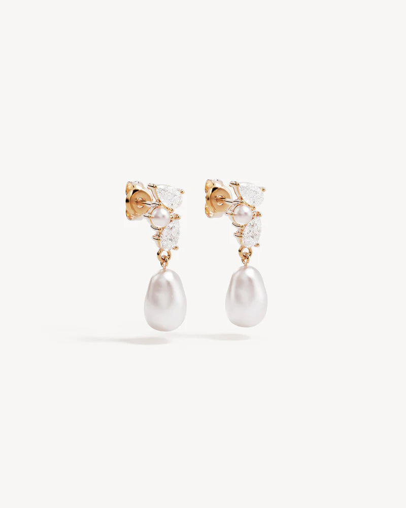 By Charlotte - The Moments in Time Pearl Drop Earrings are a classic pearl drop earring design with an asymmetrical twist, featuring pear-cut stones and pearls intentionally set as though cascading down the ear. This keepsake is designed for marking moments in time.&nbsp;

18k Gold Vermeil: 2.5 microns of 18 carat gold coating a sterling silver base.&nbsp;

Set with round and baroque freshwater pearls and pear cut cubic zirconias.&nbsp;

Sold as a pair.&nbsp;
