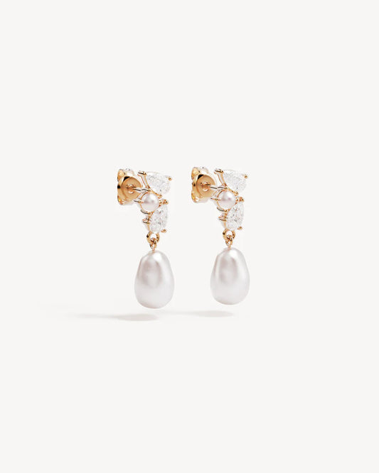By Charlotte - The Moments in Time Pearl Drop Earrings are a classic pearl drop earring design with an asymmetrical twist, featuring pear-cut stones and pearls intentionally set as though cascading down the ear. This keepsake is designed for marking moments in time.&nbsp;

18k Gold Vermeil: 2.5 microns of 18 carat gold coating a sterling silver base.&nbsp;

Set with round and baroque freshwater pearls and pear cut cubic zirconias.&nbsp;

Sold as a pair.&nbsp;
