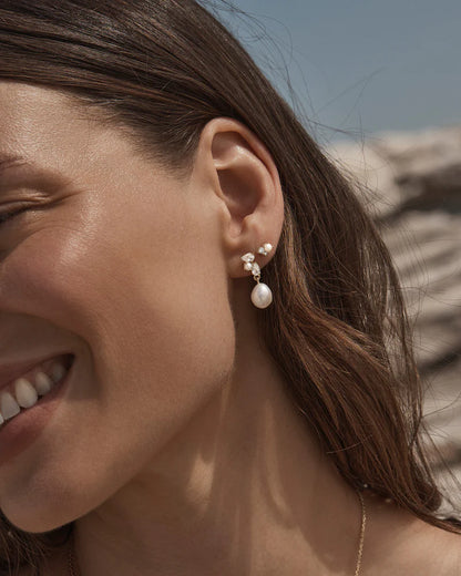 By Charlotte - The Moments in Time Pearl Drop Earrings are a classic pearl drop earring design with an asymmetrical twist, featuring pear-cut stones and pearls intentionally set as though cascading down the ear. This keepsake is designed for marking moments in time.&nbsp;

18k Gold Vermeil: 2.5 microns of 18 carat gold coating a sterling silver base.&nbsp;

Set with round and baroque freshwater pearls and pear cut cubic zirconias.&nbsp;

Sold as a pair.&nbsp;
