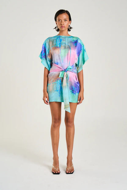 The Tie Front Dress featuring the hand-painted H20 artwork offers a versatile, figure-flattering design boasting a high neckline, modest sleeves, and a modern mini silhouette. Its wrap overlay ties at the side, allowing you to customise the length and fit to suit your style. Crafted from a silky viscose and rayon blend, this dress combines comfort with a refined finish, making it ideal for both casual and polished looks.

