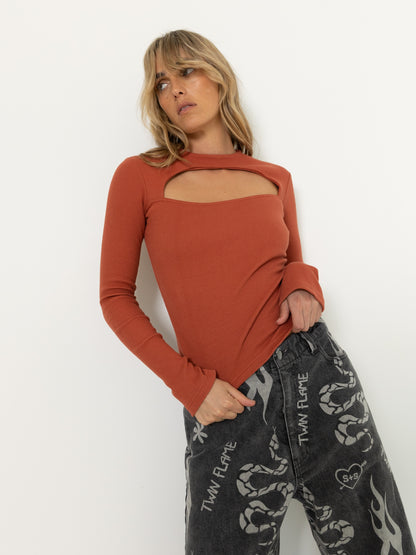 This premium CUT OUT LS TOP in RUST features thick ribbed cotton with a unique cut out feature and extra-long sleeves, delivering a sophisticated look with a hint of edginess.