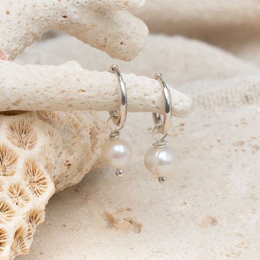 Elevate your style with our Pearl Layla Huggies, a timeless addition to your collection. These earrings feature sterling silver huggies adorned with lustrous freshwater pearls, symbolizing purity, wisdom, and maternal influence. Pearls are known for their calming and balancing properties, making these earrings not just a fashion statement, but also a source of inner peace and harmony.