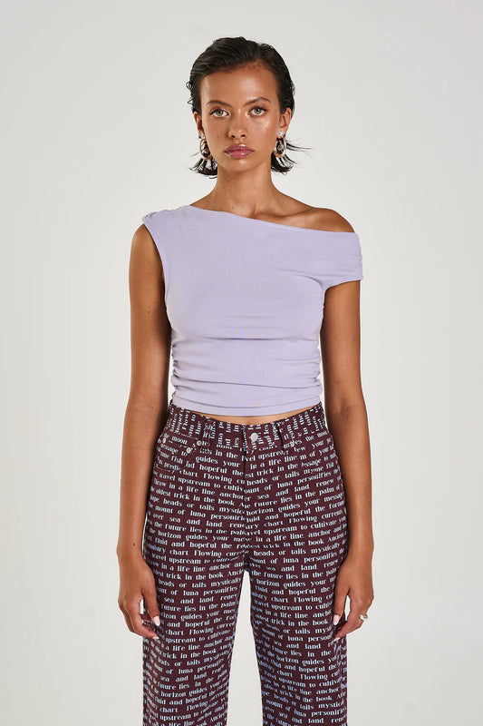 The Off Shoulder Tank in a seafoam lilac hue has been constructed from a stretchy cotton blend, featuring a ruched midsection for a flattering fit.